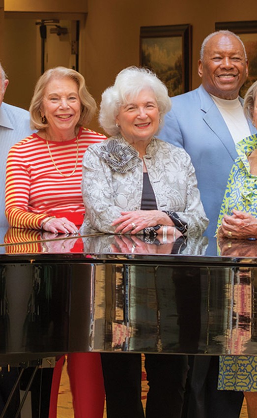 Resident ambassadors standing around a piano.