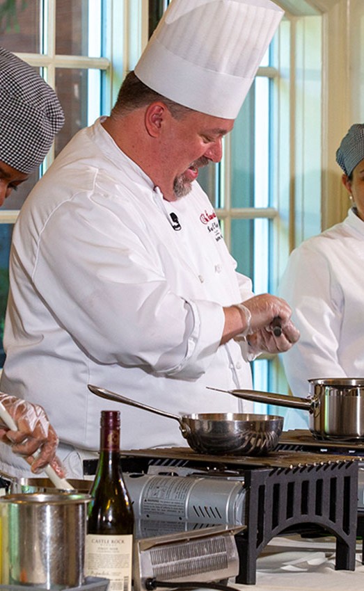 Three chefs cooking food in the dining room.