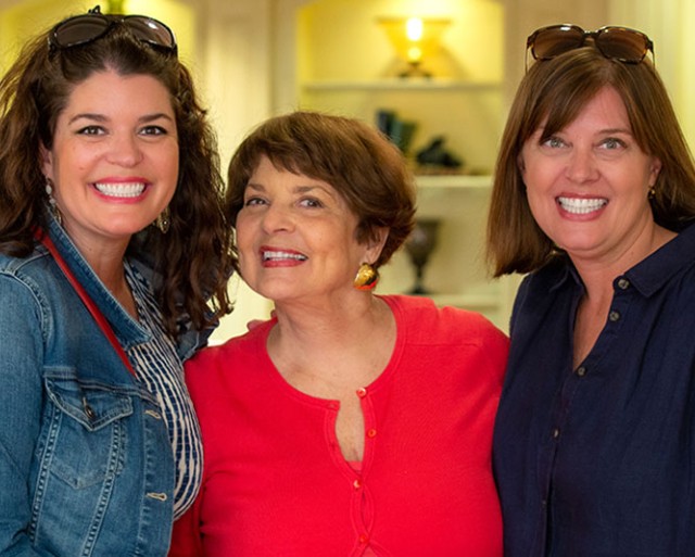 A mother smiling to the camera with her daughters.