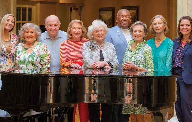 Resident ambassadors standing around a piano.