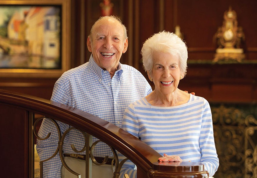 A couple standing next the the stairs smiling.