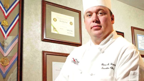 Executive Chef Brian Hardy in front of medals and certificates.