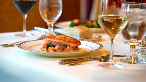 A fish dish on a fancy table with various wines.